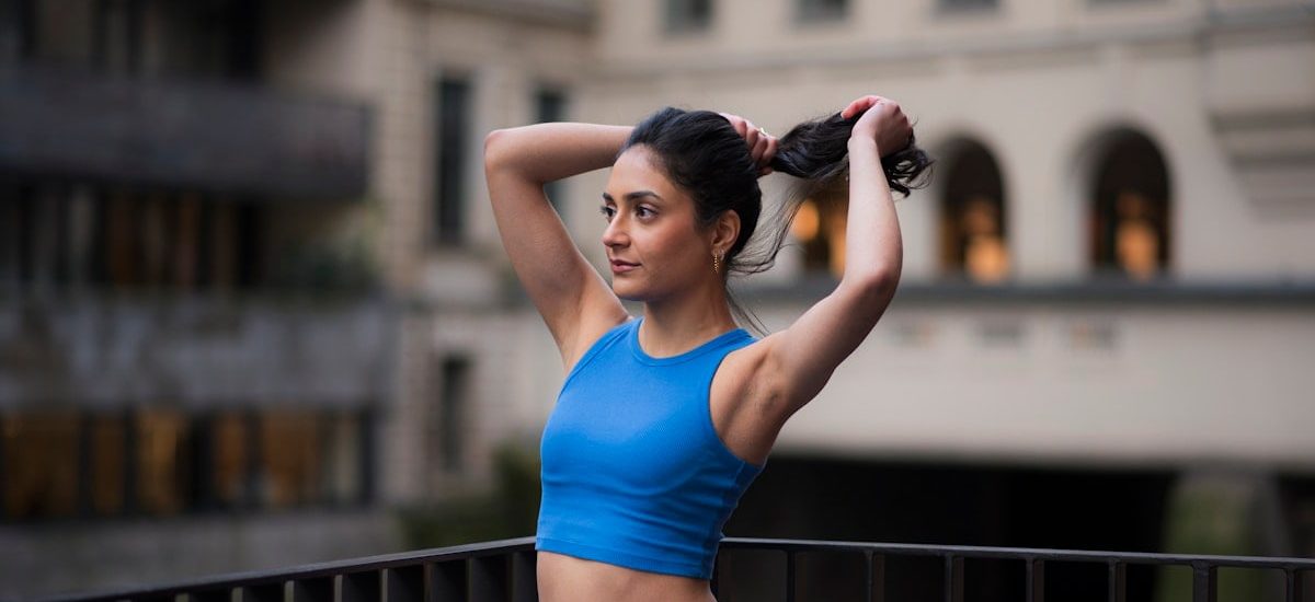 Woman in workout gear pulls her hair back.