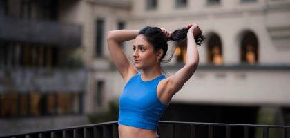 Woman in workout gear pulls her hair back.