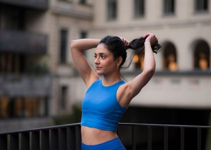 Woman in workout gear pulls her hair back.